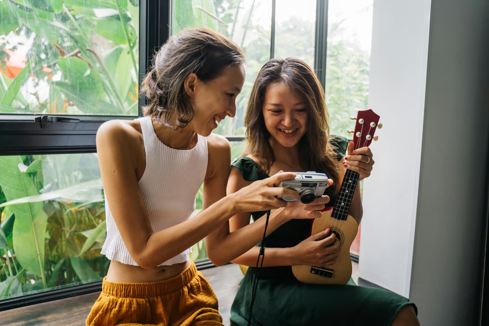 Two friends sharing a camera and a ukulele — a warm, candid moment